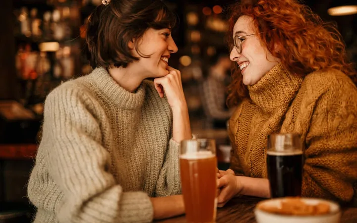 Zwei Frauen lachen sich in einer Bar an
